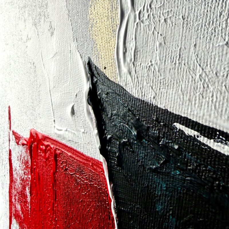 Nowoczesny obraz abstrakcyjny z czarną centralną formą, białym tłem oraz akcentami czerwieni, złota i niebieskiego, utrzymany w minimalistycznym stylu zbliżenie